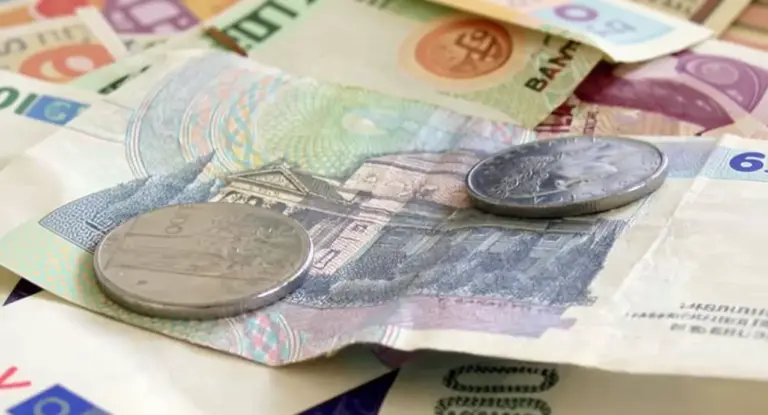 Vecchie monete da cento lire appoggiate su banconote italiane