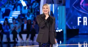 Una donna sorride sul palco illuminato durante una puntata di Grande Fratello