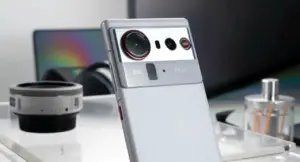 Smartphone grigio con tripla fotocamera posteriore su un tavolo con oggetti tecnologici sullo sfondo