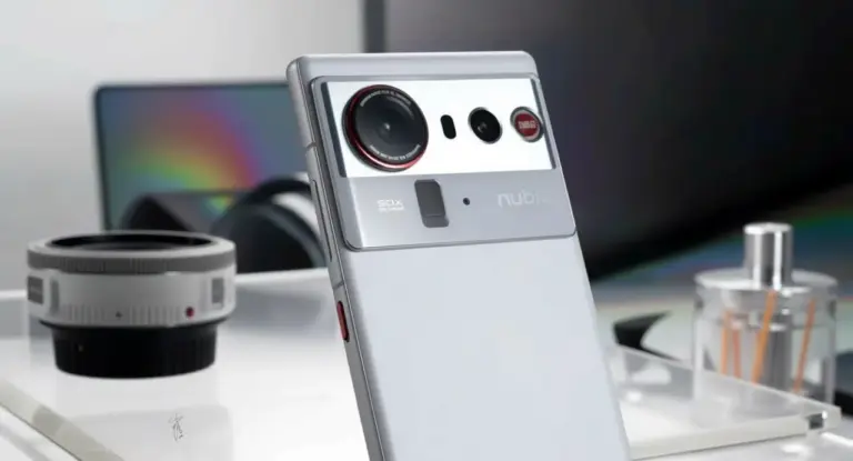 Smartphone grigio con tripla fotocamera posteriore su un tavolo con oggetti tecnologici sullo sfondo