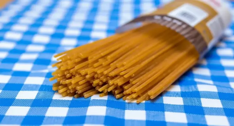 Confezione di spaghetti crudi su tovaglia a quadretti blu e bianchi