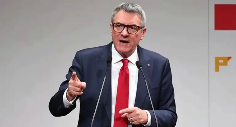 Un uomo in abito parla al microfono durante una conferenza stampa