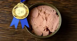 Scatoletta di tonno aperta con medaglia dorata e nastro blu accanto