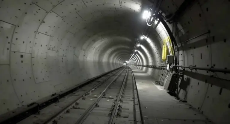 Tunnel ferroviario vuoto con binari e illuminazione artificiale