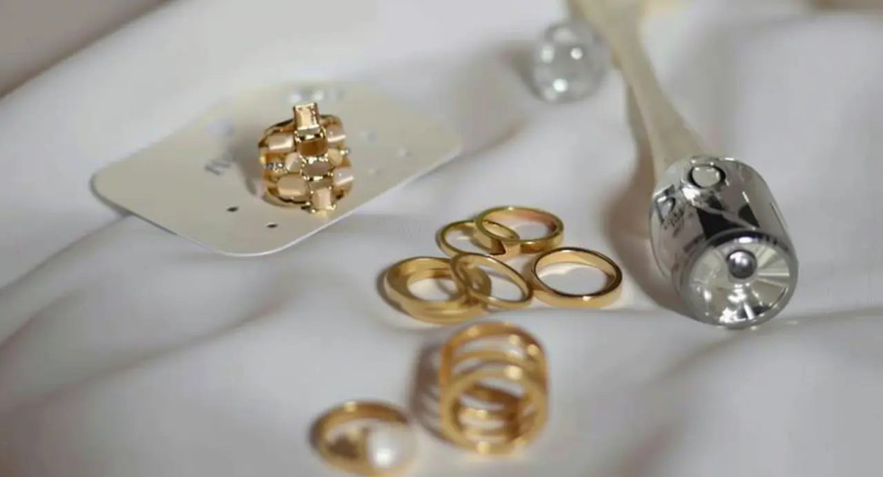 Anelli d'oro usati su una superficie bianca accanto a uno strumento argentato